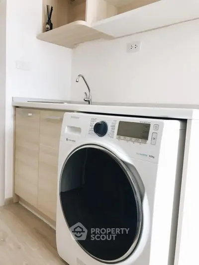 Modern laundry area with sleek washing machine and wooden cabinetry