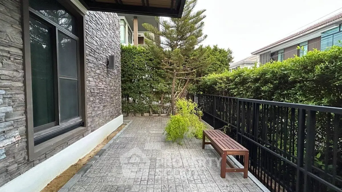Charming outdoor patio with lush greenery and stone facade, perfect for relaxation and entertaining.