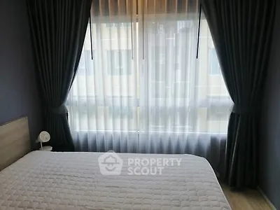 Cozy bedroom with large window and elegant curtains, perfect for natural light lovers.