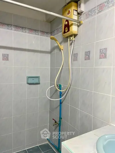 Compact bathroom with tiled walls and water heater, ideal for small spaces.
