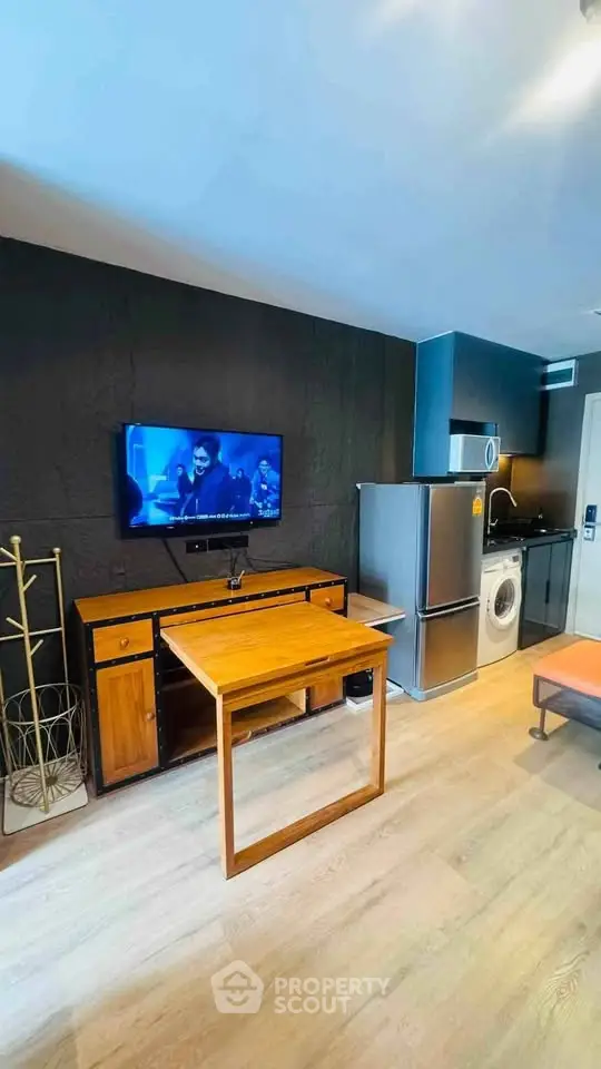 Modern living room with TV, wooden furniture, and kitchen appliances in a stylish apartment.