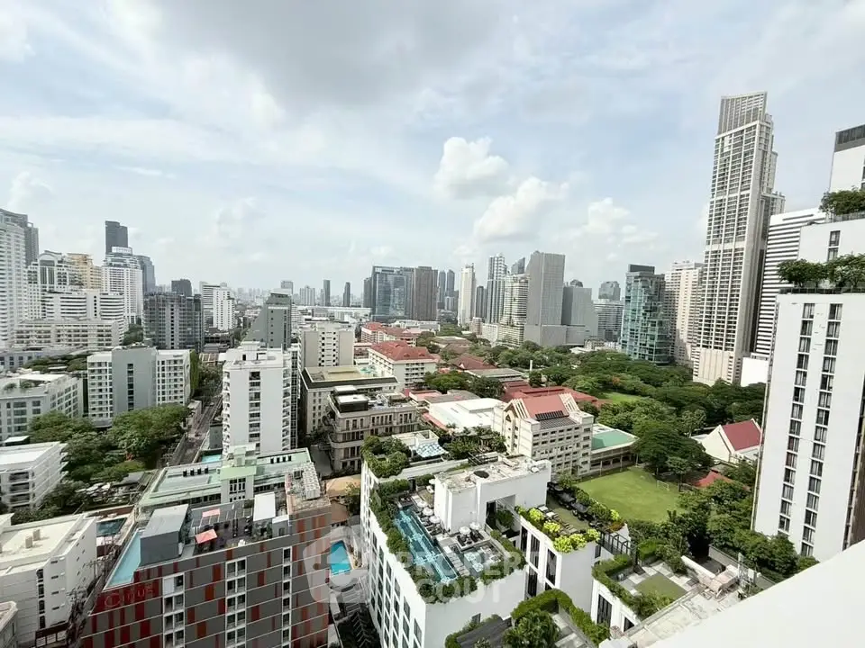 Stunning cityscape view from a high-rise building showcasing urban skyline and lush greenery.