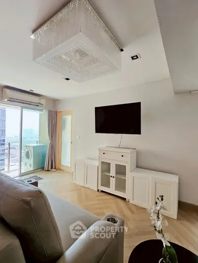 Modern living room with elegant chandelier and balcony view in luxury apartment.