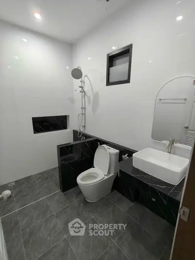 Modern bathroom with sleek black and white design, featuring a shower and stylish fixtures.