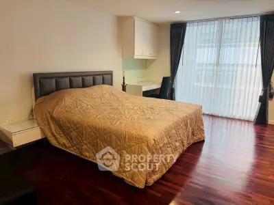 Spacious bedroom with elegant hardwood floors and large windows for natural light.