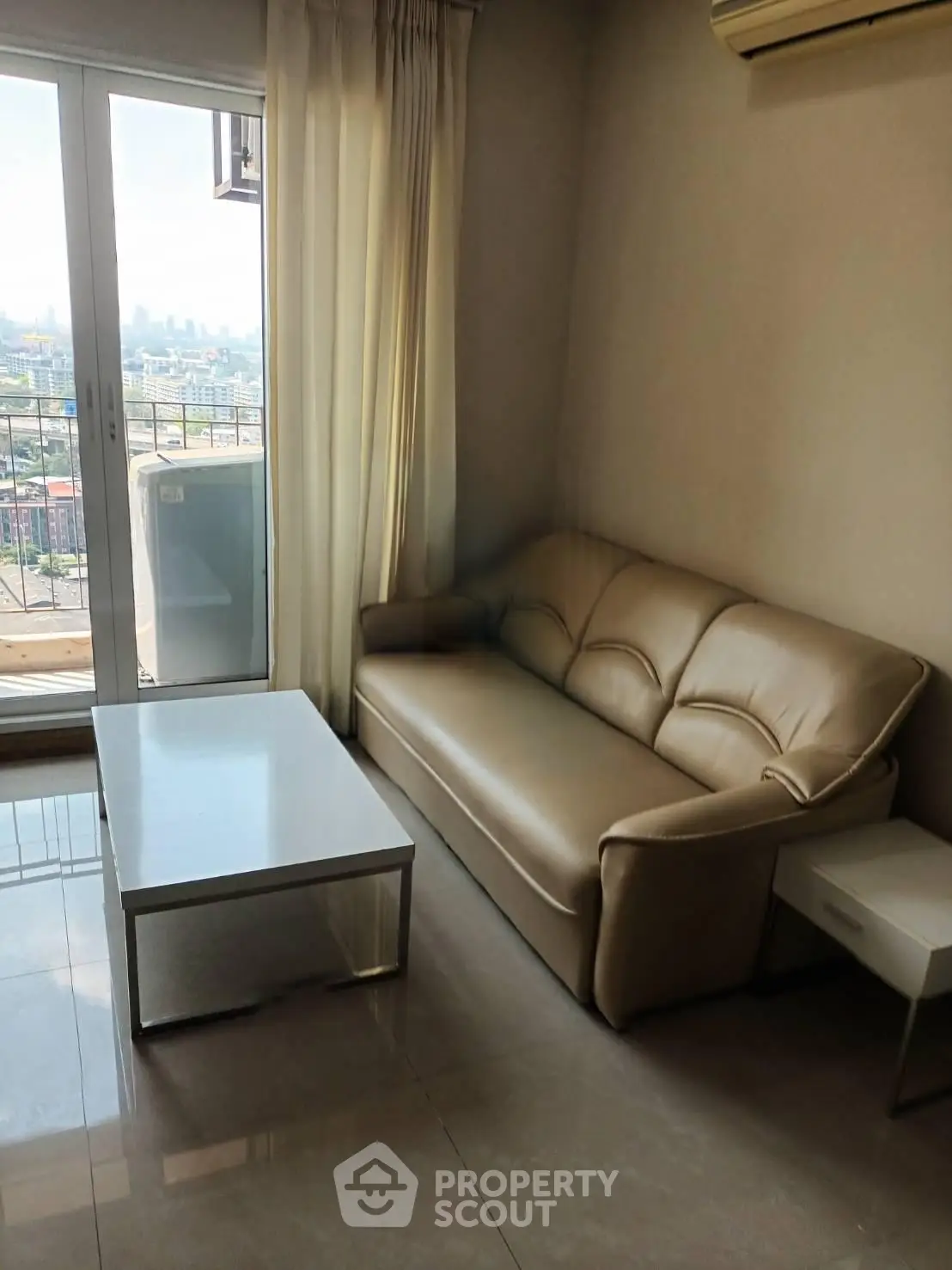 Cozy living room with leather sofa and city view balcony in modern apartment.