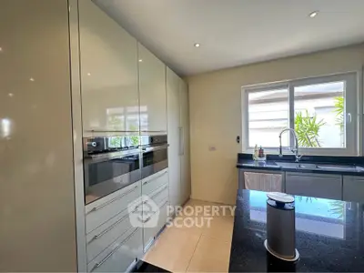 Modern kitchen with sleek cabinetry and large window for natural light