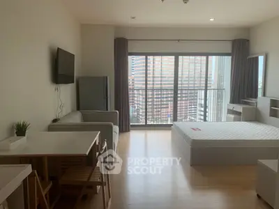 Modern studio apartment with large windows and city view, featuring a cozy living area and sleek furniture.
