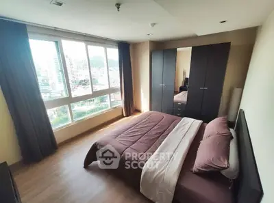 Spacious bedroom with large window offering city view and modern furnishings.
