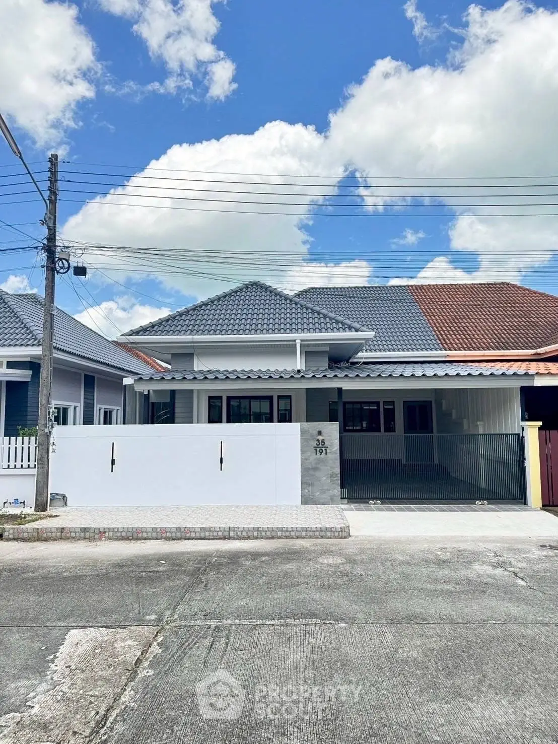 Charming single-story house with modern roof design and spacious driveway under a bright blue sky.