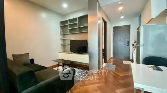 Modern living room with sleek furniture and wooden flooring, featuring a TV and open shelving.