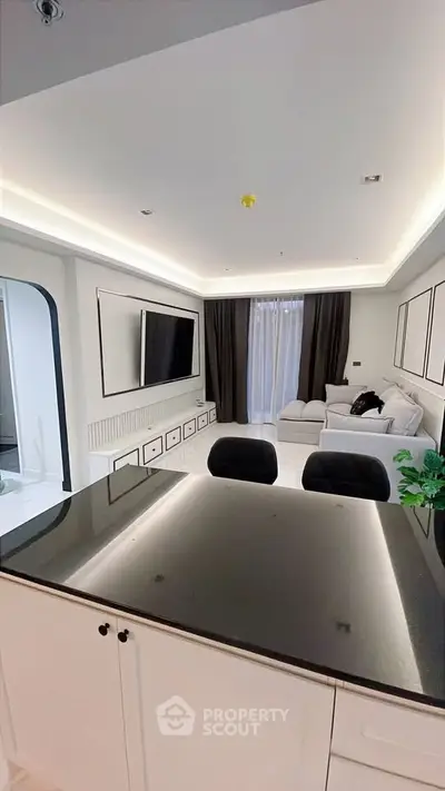 Modern open-layout living room with sleek design and elegant furnishings, featuring a spacious kitchen island.