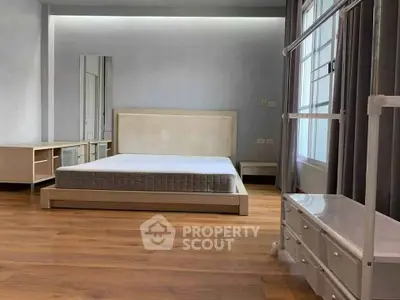 Spacious bedroom with modern wooden flooring and large window