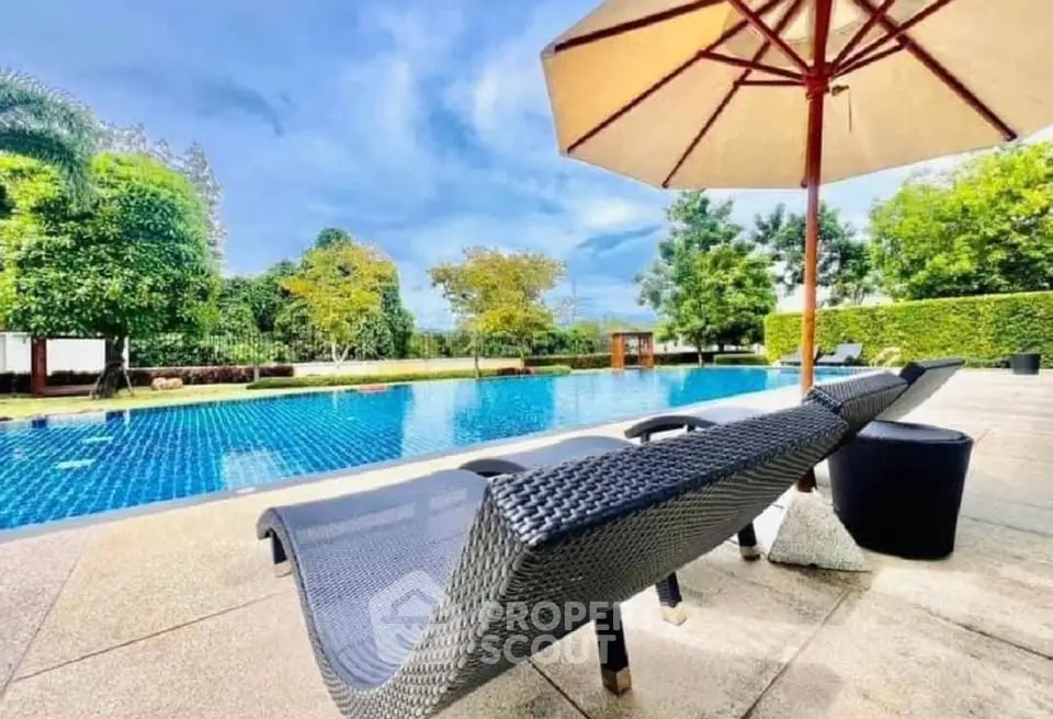 Luxurious outdoor pool area with sun loungers and umbrella, perfect for relaxation and leisure.