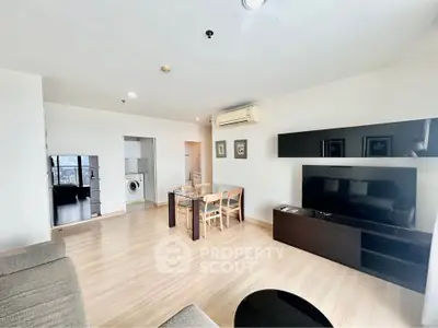 Spacious modern living room with dining area and large TV, featuring sleek wooden flooring and contemporary decor.