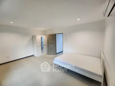 Spacious minimalist bedroom with white furniture and ample natural light