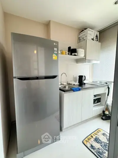 Modern compact kitchen with stainless steel fridge and sleek cabinetry
