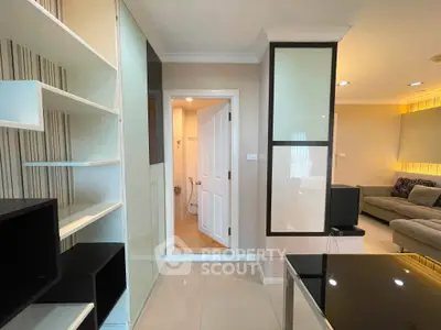 Modern living room with sleek shelving and open bathroom door, featuring neutral tones and contemporary design.