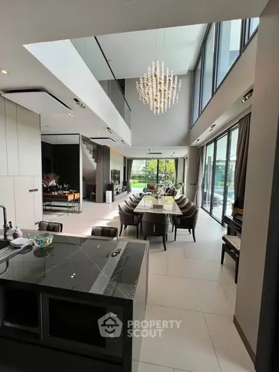 Luxurious open-plan living and dining area with high ceilings and modern chandelier.