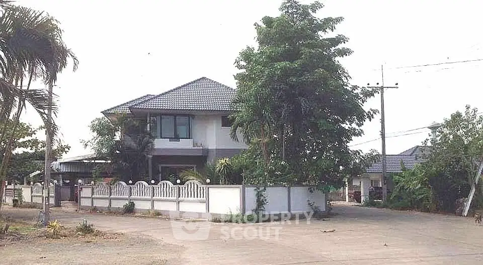 Charming two-story house with tiled roof and lush greenery in a serene neighborhood.