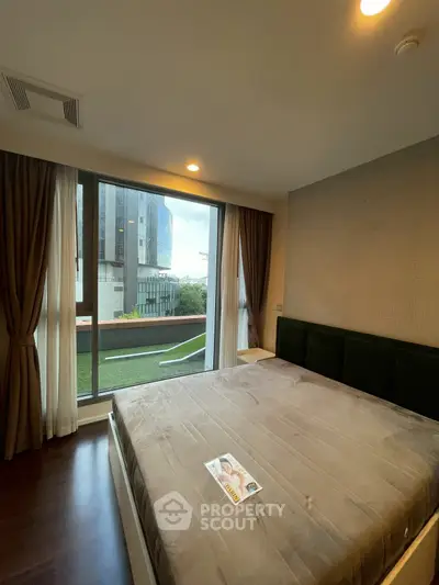 Spacious bedroom with large window and modern decor in urban apartment