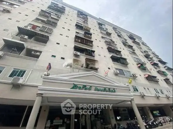 Modern multi-story residential building with balconies and air conditioning units.