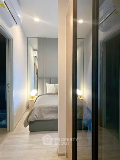 Modern bedroom with sleek design and ambient lighting, featuring mirrored walls and cozy bedding.