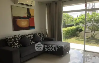Spacious living room with modern sofa and garden view, perfect for relaxation and entertaining.