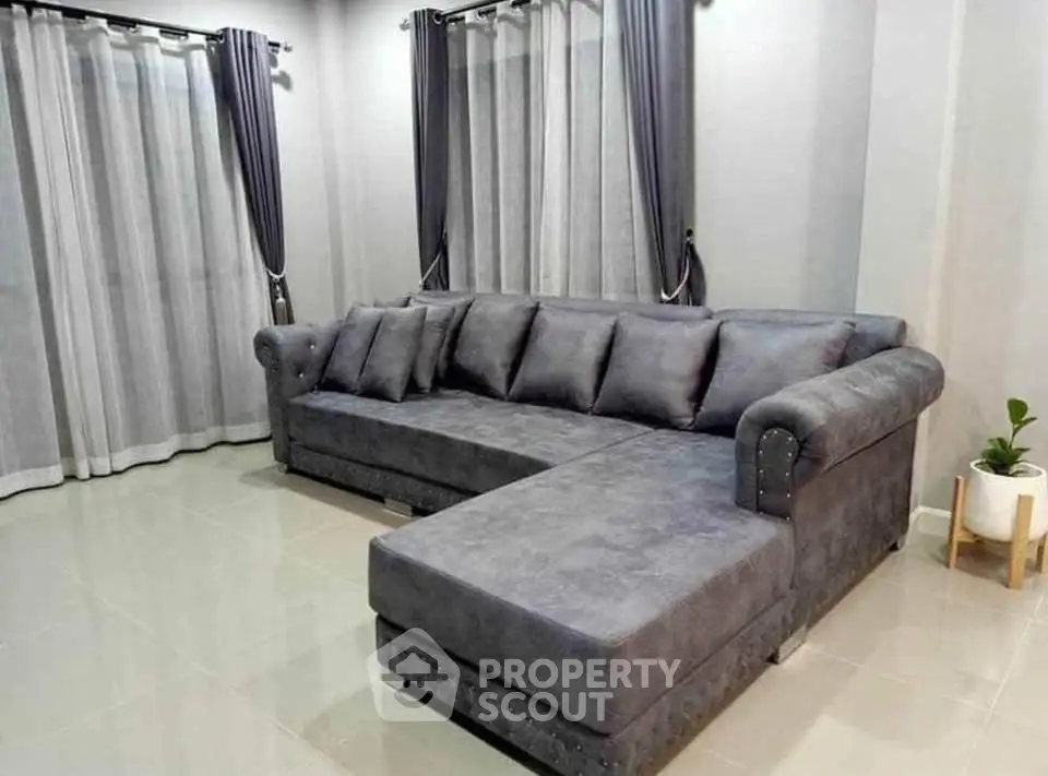 Spacious living room with modern gray sectional sofa and elegant curtains.