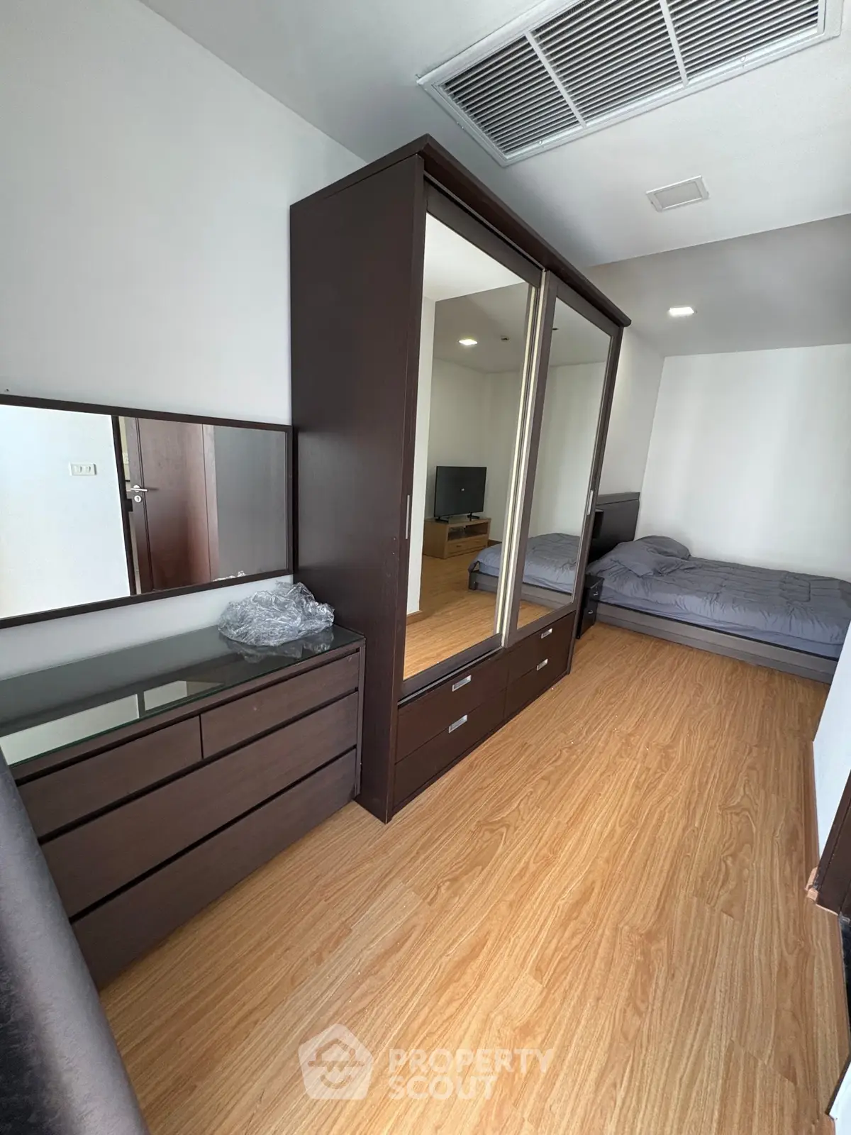 Modern bedroom with wooden flooring and mirrored wardrobe