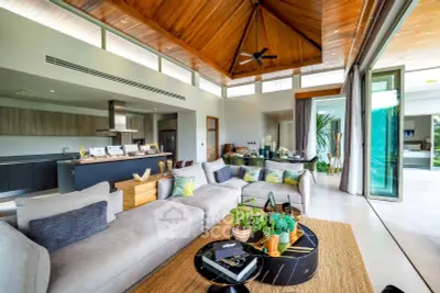 Luxurious open-plan living room with modern kitchen and pool view, featuring high wooden ceilings and elegant decor.