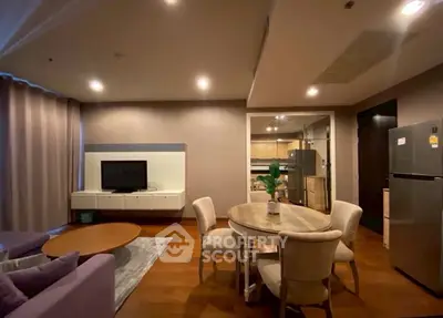 Modern living room with dining area and kitchen, featuring elegant furniture and warm lighting.