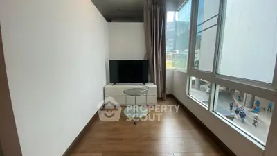 Modern living room with large windows and sleek TV setup in urban apartment.