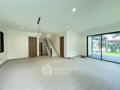 Spacious modern living room with large windows and staircase, perfect for family gatherings.