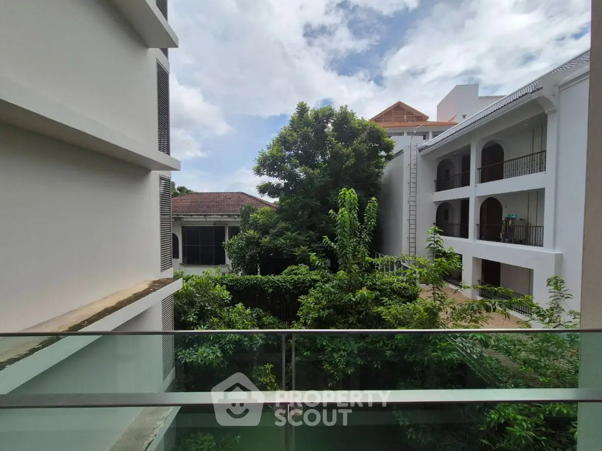 Stunning view from modern balcony overlooking lush greenery and elegant architecture.