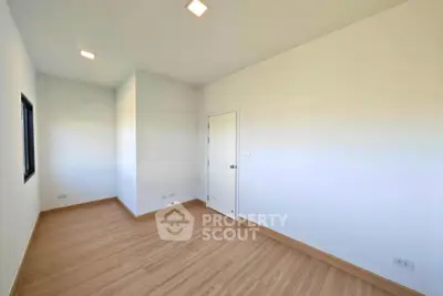 Spacious empty room with wooden flooring and white walls, perfect for customization.