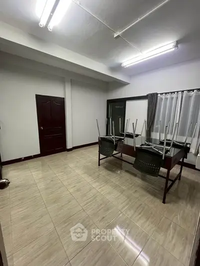 Spacious room with tiled flooring and modern lighting, ideal for versatile use.