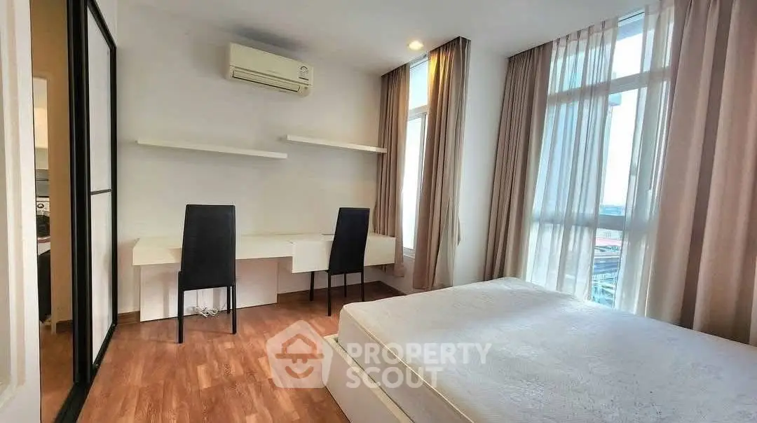 Spacious bedroom with modern furniture and large windows offering natural light.