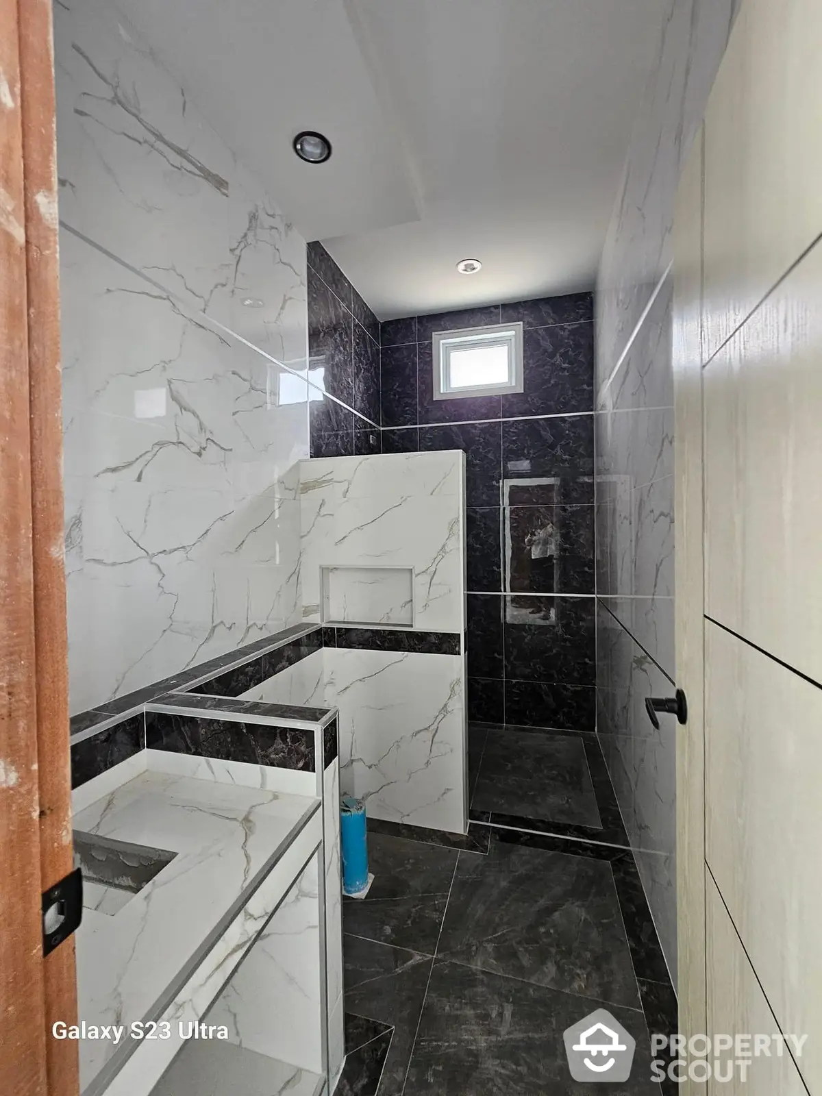 Luxurious bathroom with marble tiles, modern glass shower, and sleek design elements, perfect for upscale properties.