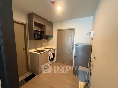 Modern kitchen with sleek cabinetry, washing machine, and fridge in compact layout.