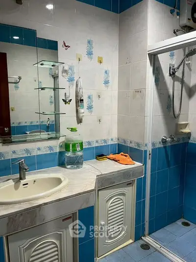 Charming bathroom with blue and white tiles, featuring a shower and vanity area.
