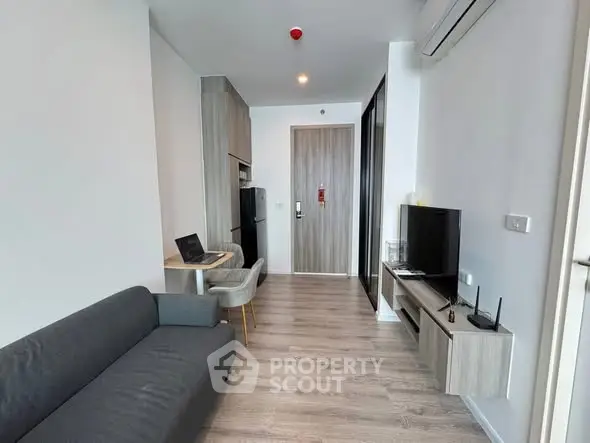 Modern living room with sleek furniture and open layout, featuring a cozy sofa and wall-mounted TV.