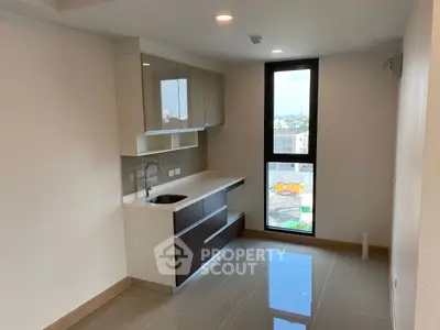 Modern kitchen with sleek cabinetry and large window offering city views.