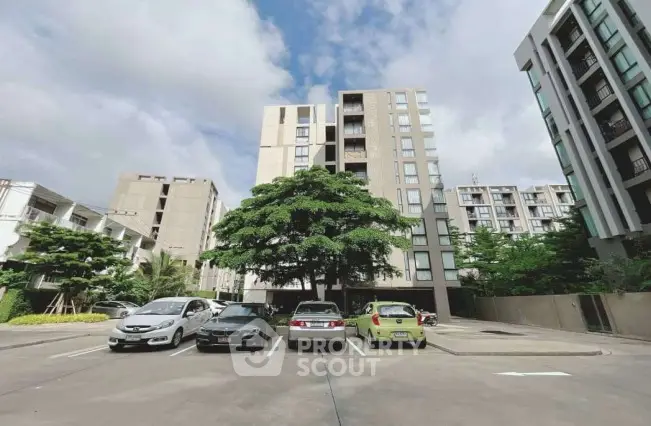 Modern apartment building with spacious parking area and lush greenery