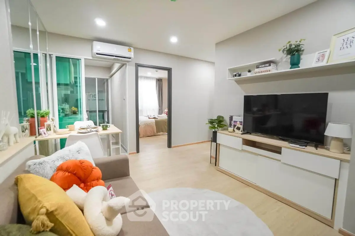 Modern living room with cozy decor and open view to bedroom, featuring stylish furniture and bright lighting.