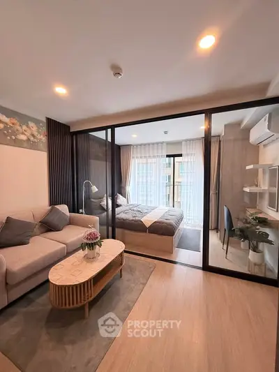 Modern studio apartment with glass partition, cozy living area, and stylish bedroom.