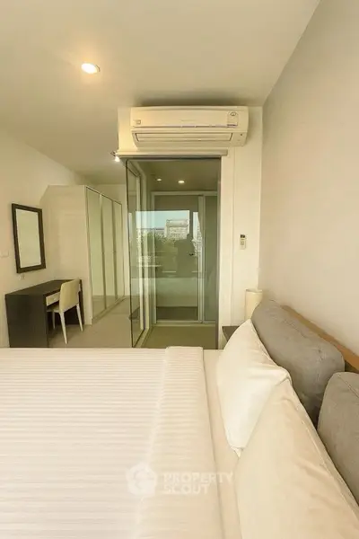 Modern bedroom with air conditioning and balcony access in a stylish apartment.