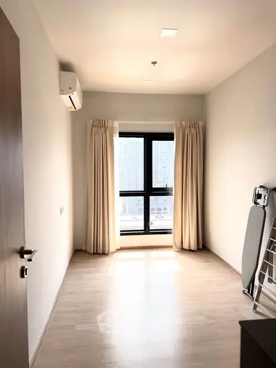 Bright and airy bedroom with large window and modern air conditioning unit, perfect for urban living.