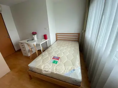 Cozy bedroom with single bed, desk, and natural light from large window.