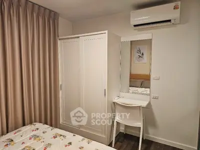 Cozy bedroom with wardrobe and vanity desk, featuring air conditioning and floral bedding.